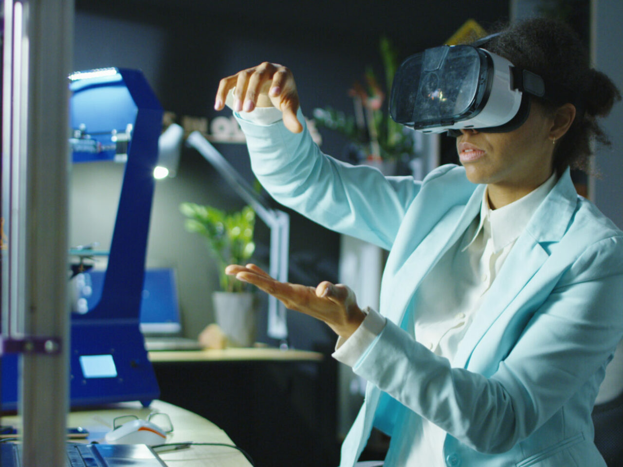 Frau trägt ein VR-Headset, während sie an einem Ingenieurprojekt im Labor mit dreidimensionalem Druck arbeitet.