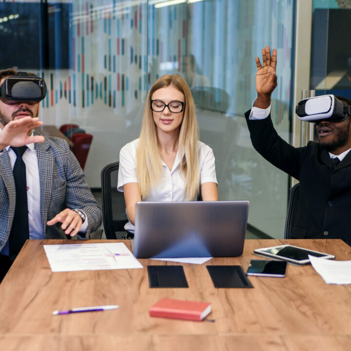 Geschäftsleute verwenden Virtual-Reality-Brillen während einer Beratungssitzung. Ein Team von Entwicklern testet Virtual-Reality-Headsets und diskutiert neue Ideen zur Verbesserung des visuellen Erlebnisses in ihrem Unternehmen.
