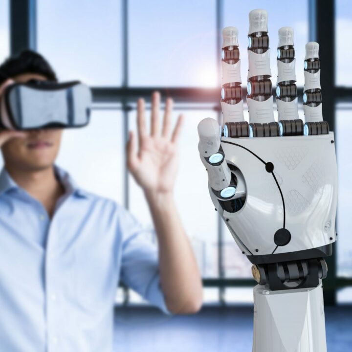 Der Mann im Hintergrund probiert eine VR-Brille aus. Die künstliche Hand des Roboters im Vordergrund wiederholt seine Bewegungen.