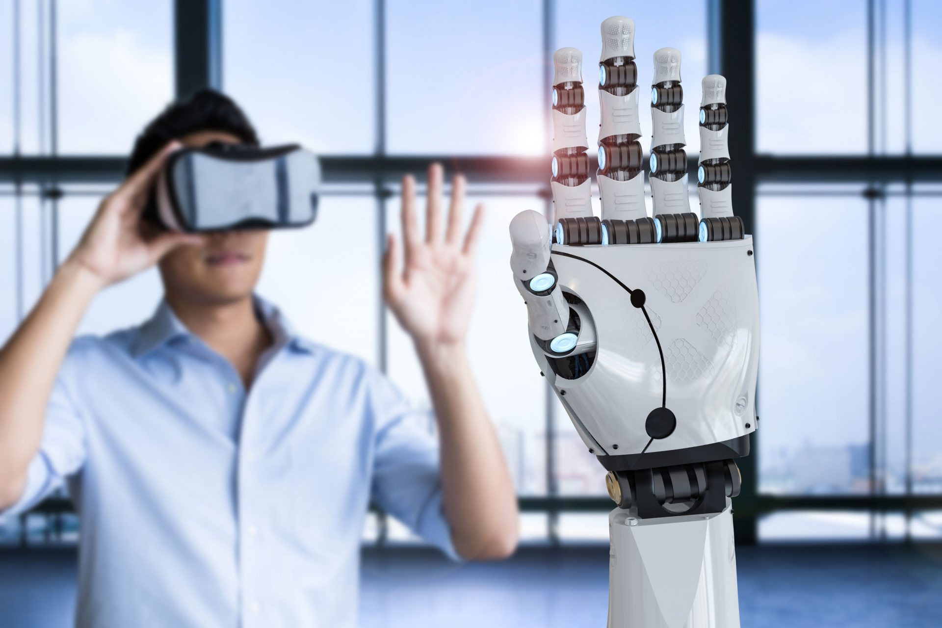 Der Mann im Hintergrund probiert eine VR-Brille aus. Die künstliche Hand des Roboters im Vordergrund wiederholt seine Bewegungen.