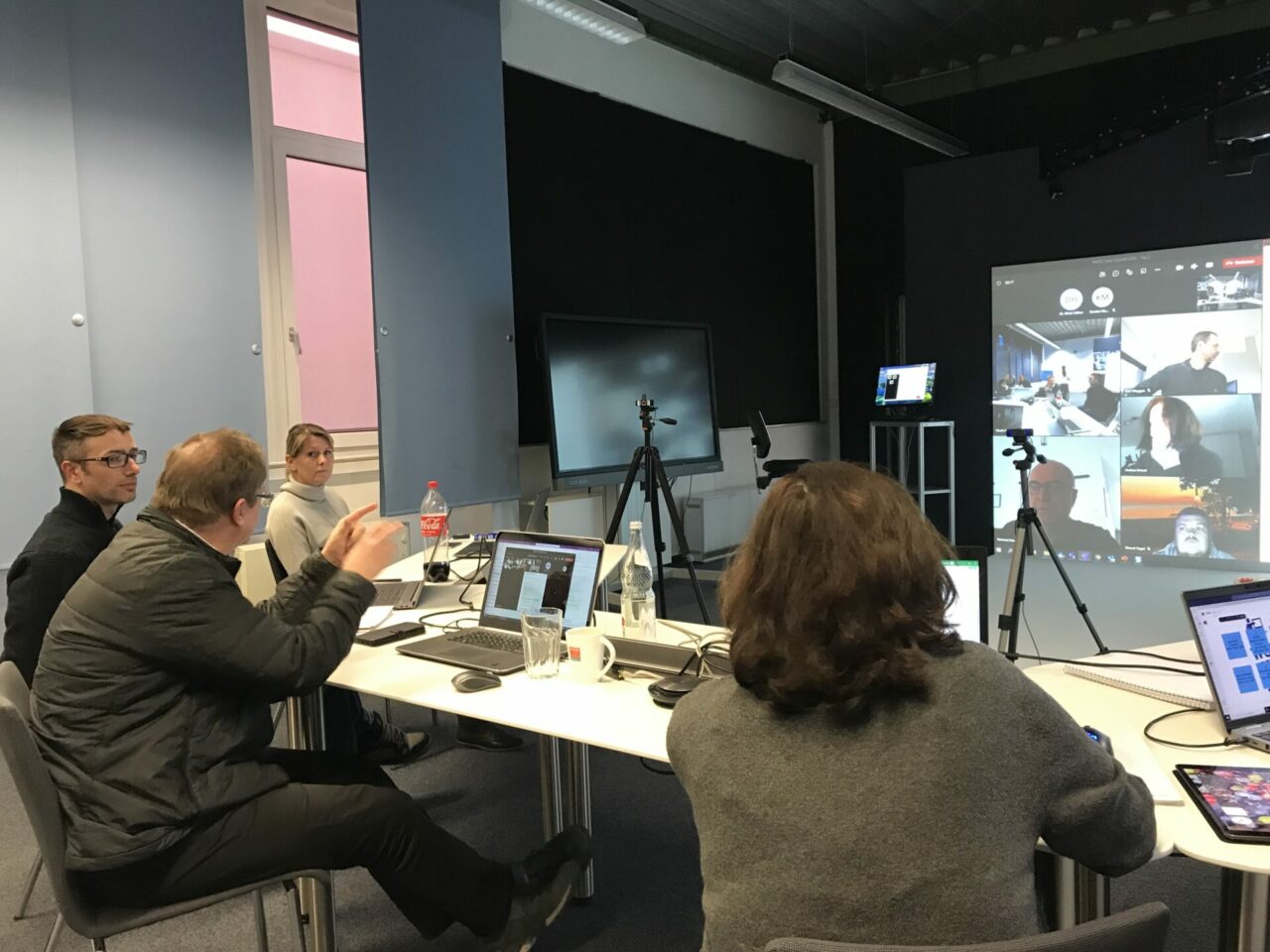 Ein Teamtraining: Auf dem Bildschirm werden die Elemente der virtuellen Realität (VR) gezeigt. Die Menschen diskutieren miteinander.