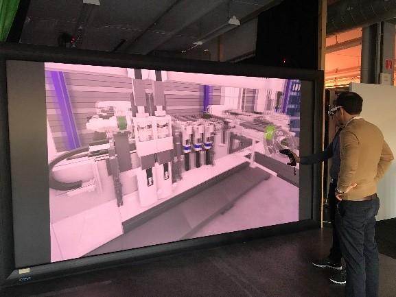 Die Arbeiter mit VR-Brillen besprechen den Aufbau einer Maschine, die auf dem Bildschirm gezeigt wird.