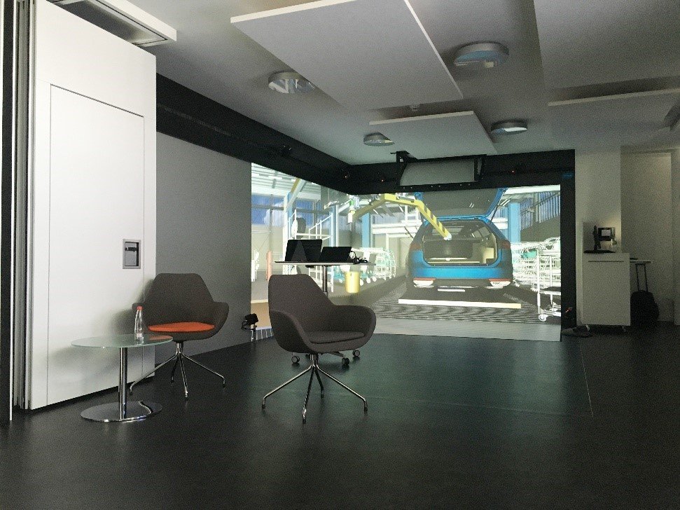 Ein Raum mit einem Bildschirm, auf dem sich ein virtuelles Auto befindet.